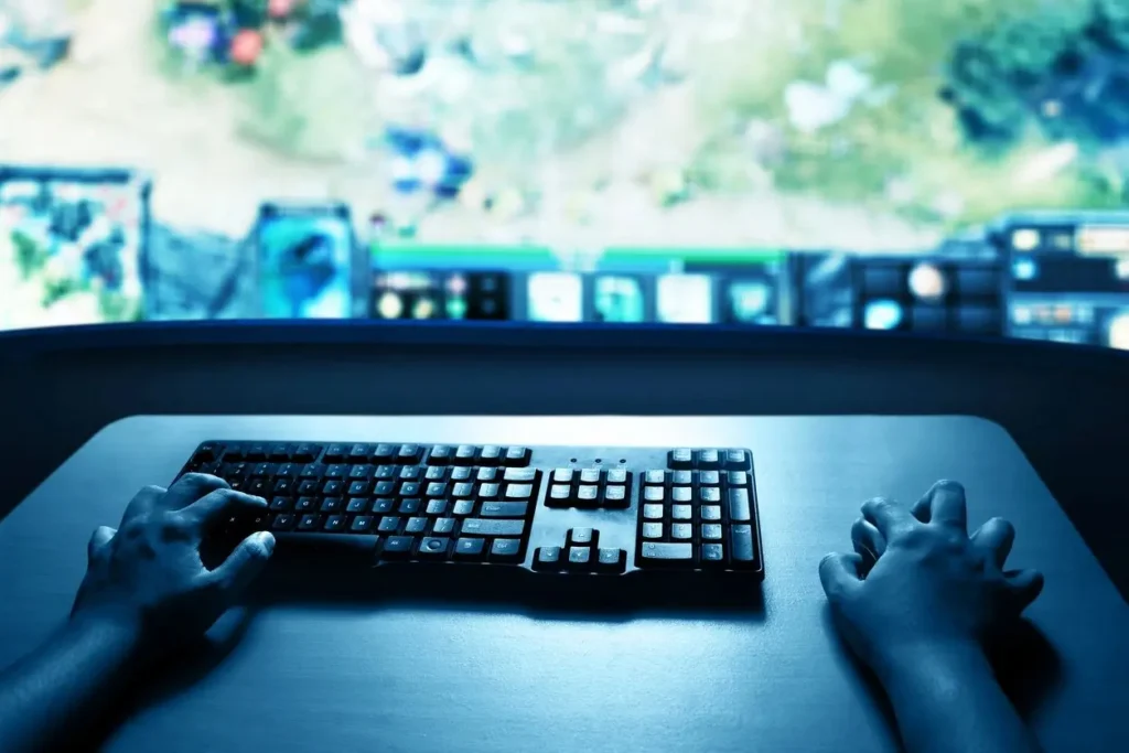 Gaming desk with a keyboard and screen under blue lighting