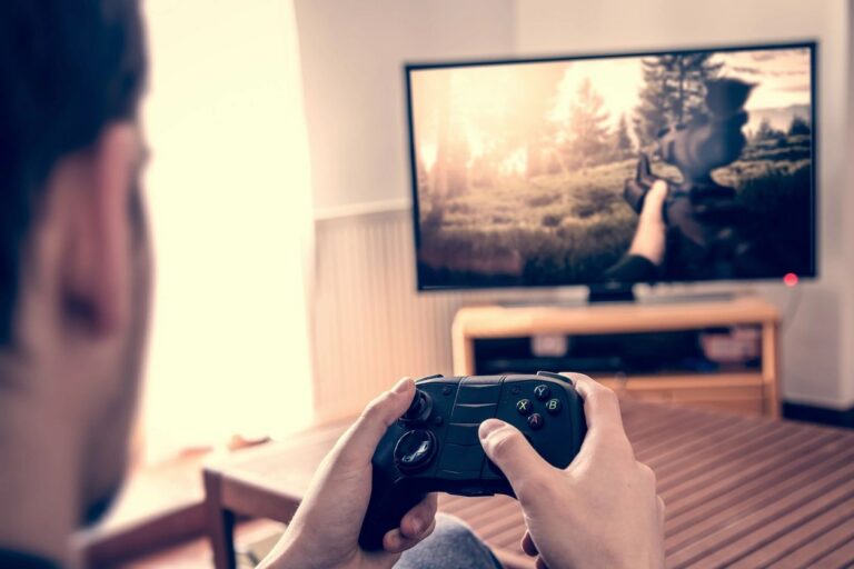 Hands holding a game controller in front of a television