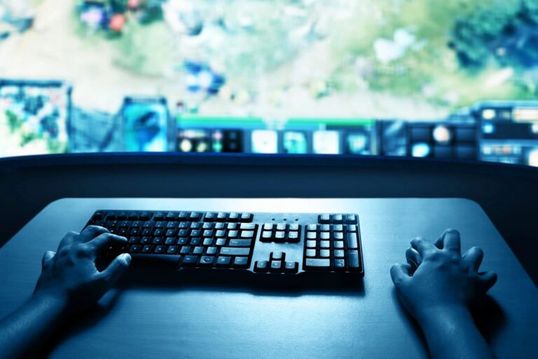 Gaming desk with a keyboard and screen under blue lighting
