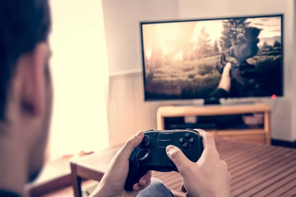 Hands holding a game controller in front of a television